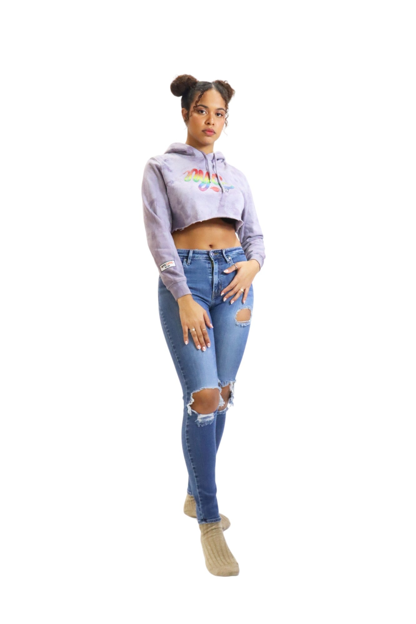 A woman wearing a light purple cropped hoodie with a rainbow serpent graphic looks off to the side, showcasing the hoodie's fit and sleeve detail.