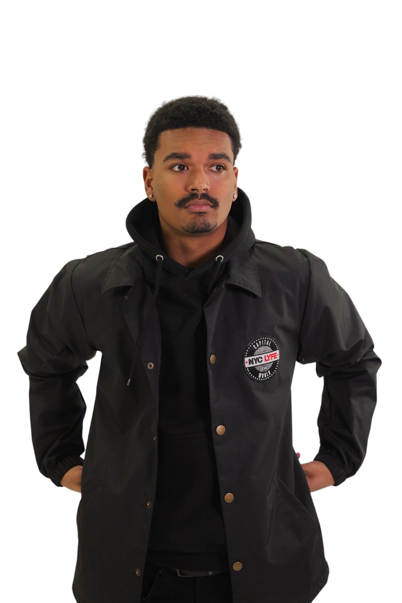 Front view of a model wearing a black coach's jacket. On the left chest is a circular embroidered patch with the words 'Original NYC LYFE'.
