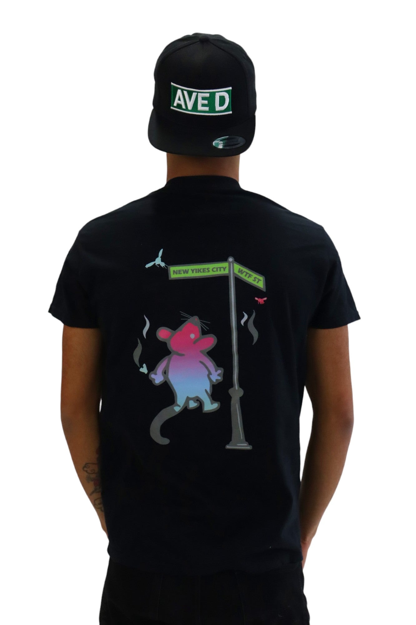 Back view of a model wearing a black t-shirt. The back has a cartoon graphic of a stressed-out rat standing at a street sign for 'New Yikes City' and 'WTF ST'.