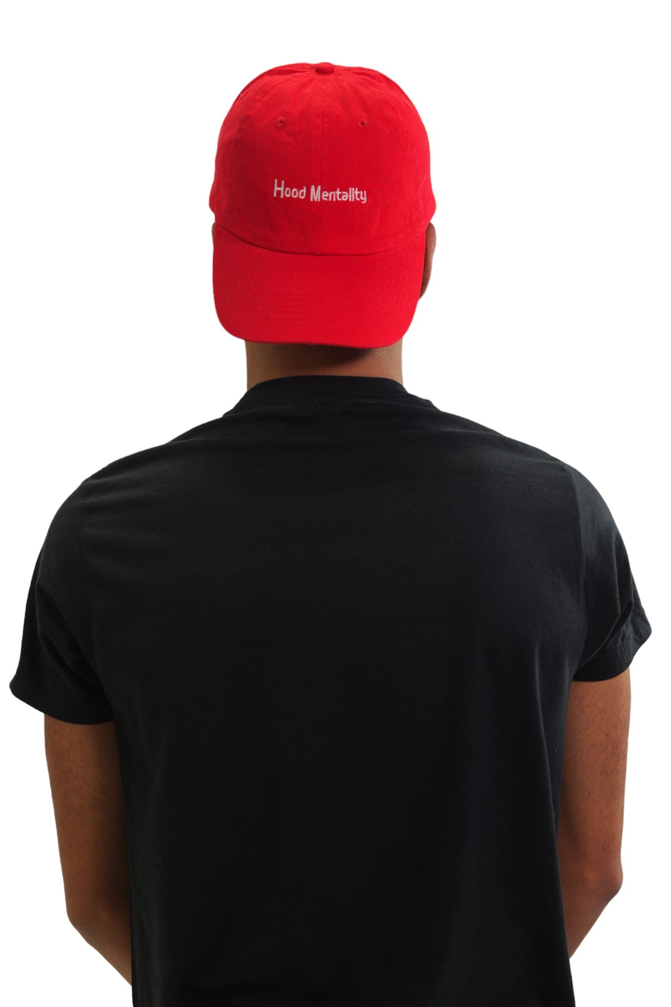 A young man with a mustache poses in a black short-sleeve t-shirt and a red baseball cap against a white background. This is the back of the t-shirt that has a graphic of Pablo Escobar with his teeth colored gold and bold red text over it that says 'Traffic-King'. The red cap has 'HOOD Mentality' embroidered in white.