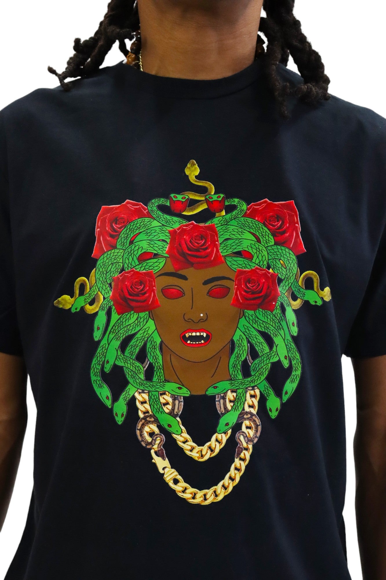 Front Close up view of a model wearing a black t-shirt. The shirt features a large, colorful graphic of Medusa as a Black woman with green snakes and red roses for hair, glowing red eyes, and a gold chain necklace.