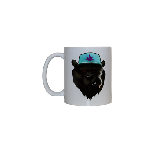 Front view of a white ceramic mug. The mug has a graphic of a snarling black bear with red eyes, wearing a light blue hat with a purple cannabis leaf.