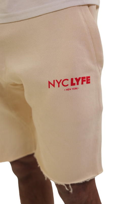 A close-up shot of a person's pocket area on off-white fleece bottoms. The 'NYC LYFE • NEW YORK •' logo is printed in red below the pocket.