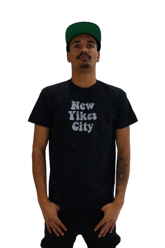 Front view of a model wearing a black t-shirt with the words 'New Yikes City' printed on the chest in a light blue, bubbly font.