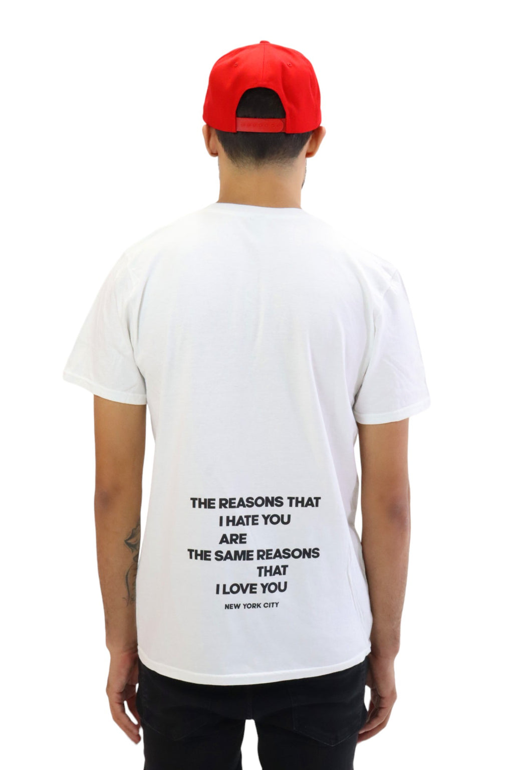 Back view of a model wearing a white t-shirt. The shirt features a quote in black text that reads: 'THE REASONS THAT I HATE YOU ARE THE SAME REASONS THAT I LOVE YOU' with 'NEW YORK CITY' printed underneath.