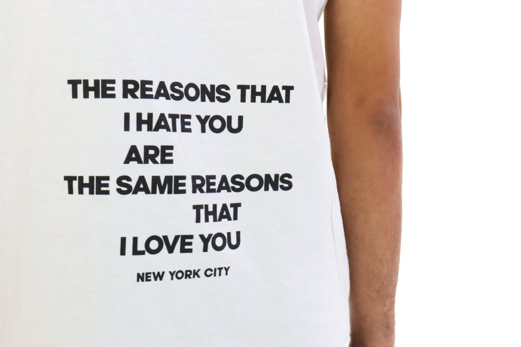 Close Up Back view of a model wearing a white t-shirt. The shirt features a quote in black text that reads: 'THE REASONS THAT I HATE YOU ARE THE SAME REASONS THAT I LOVE YOU' with 'NEW YORK CITY' printed underneath.