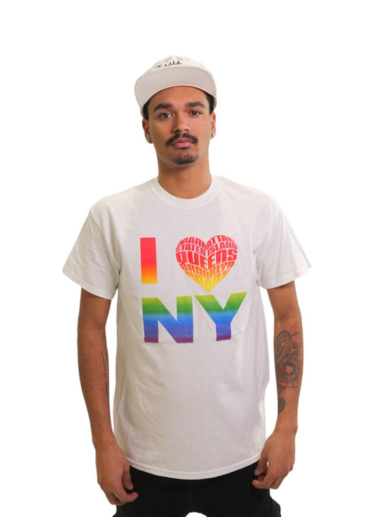 A man models a white t-shirt featuring a rainbow-gradient design that reads 'I ❤️ NY'. The heart graphic is filled with the names of the five boroughs: Manhattan, Staten Island, Queens, the Bronx, and Brooklyn.
