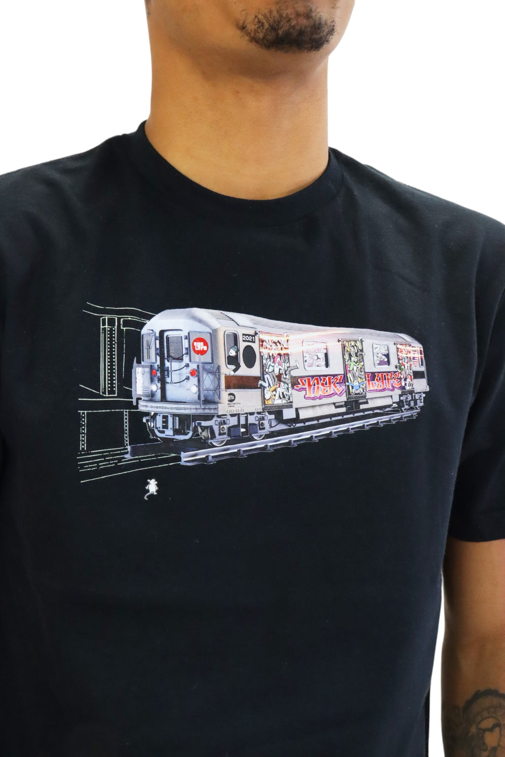 A man models a black t-shirt featuring a detailed graphic of a vintage New York City subway train. The entire side of the train car is covered in colorful, elaborate graffiti as it emerges from a dark tunnel.