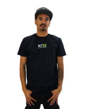 Front view of a model wearing a black t-shirt. On the left chest is a small logo in green and white that reads 'NYSE' with the full text 'New York Survival Education' printed below it.